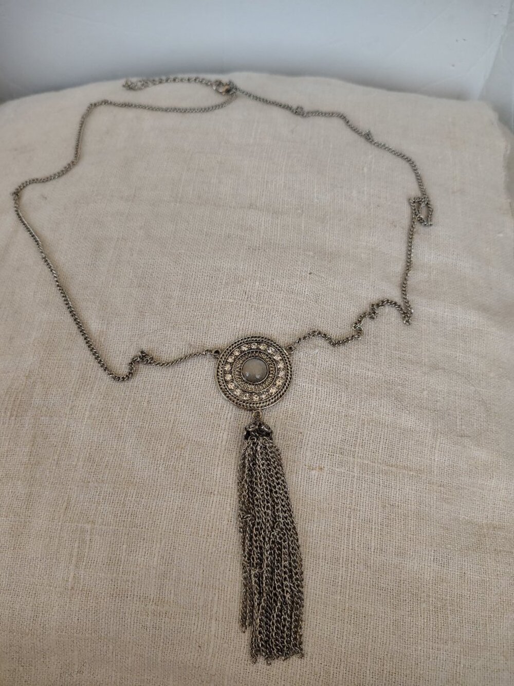 Silver tone Long chain necklace with a round metal pendant and rhinestone accent